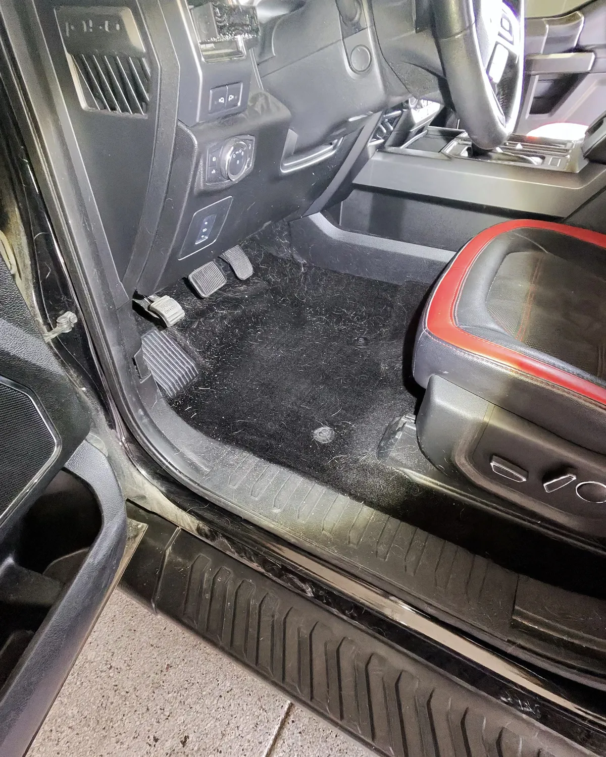 Ford F-150 driver floor covered in pet hair before detailing